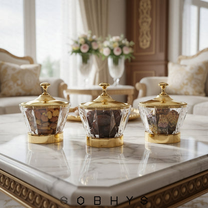 Three decorative glass containers with gold lids on a marble table in a luxurious room.