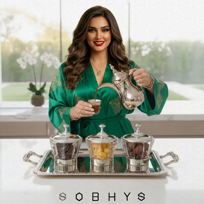 Woman in a green robe pouring tea from a silver teapot with a tray of tea accessories on a white surface. Sobhys Silver-Tone Acrylic Bowl – Top View Showing Diamond-Cut Facets and Ornate Lid Detail
