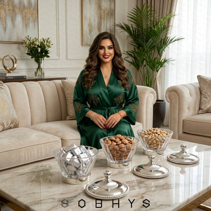 Woman in a green robe sitting in a stylish living room with decorative items on the table. Sobhys Luxury Acrylic Serving Bowl – Silver-Tone Base Detail and Rope-Edge Border
