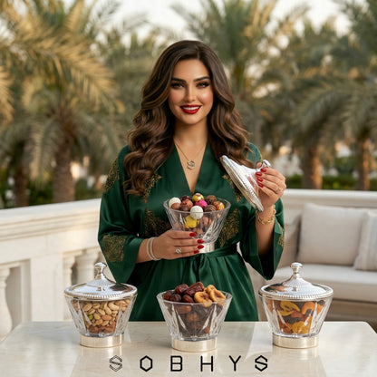 Woman holding a bowl of snacks with palm trees in the background, featuring the brand 'Sobhys'. Sobhys Silver-Tone Acrylic Bowl – Light Refraction Through Diamond-Cut Facets
