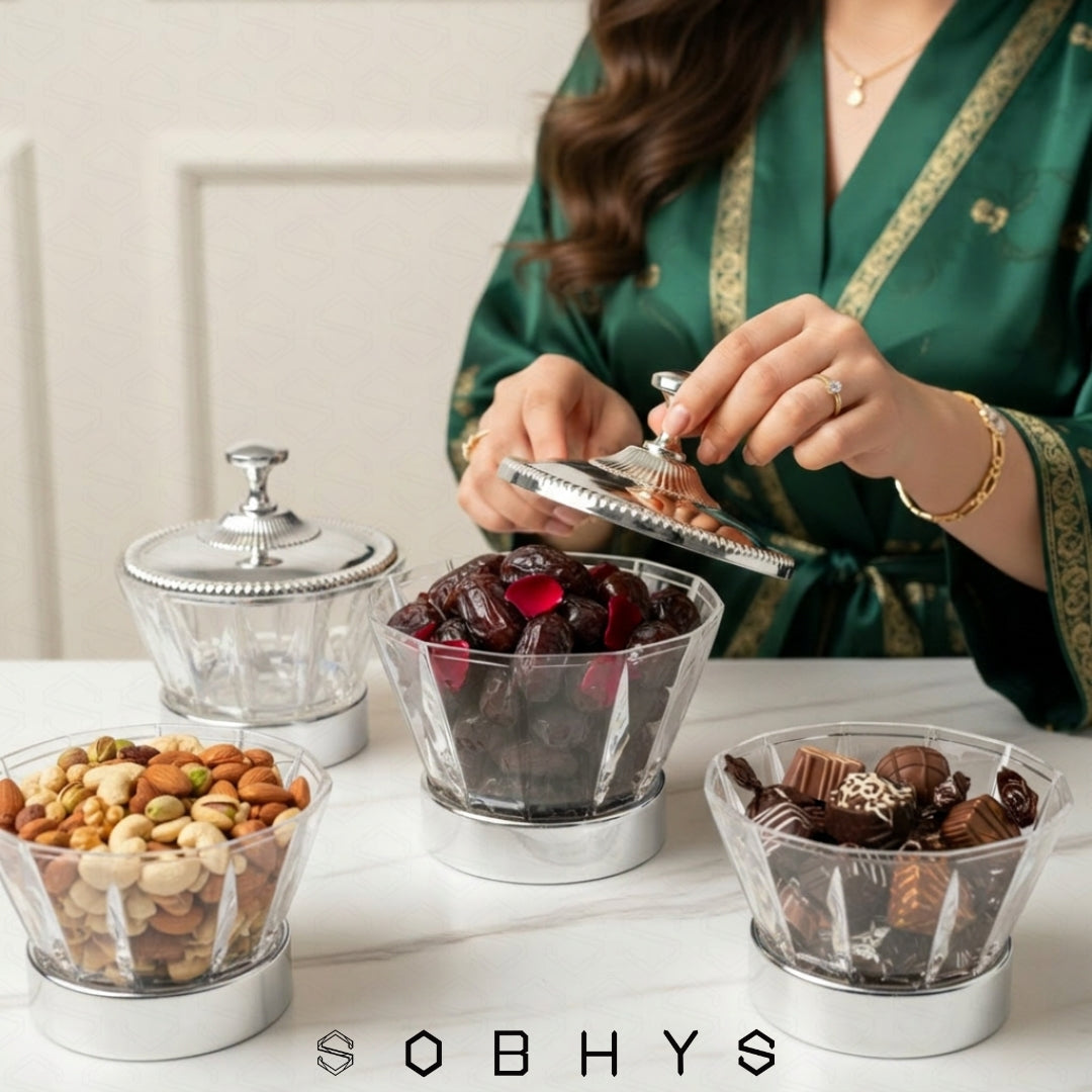 Person in a green robe selecting snacks from glass containers on a table, with 'SOBHYS' branding. Sobhys Luxury Crystal Bowl – Silver-Tone Ribbed Finial Handle Close-Up
