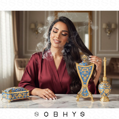 Luxury Mabkhara incense burner ornate base Royal Blue Gold UAE gift
Woman with decorative items on a table, featuring the Sobhys brand.